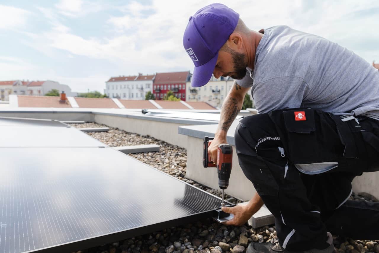 Zwei Handwerker mit Solarmodul auf Dach