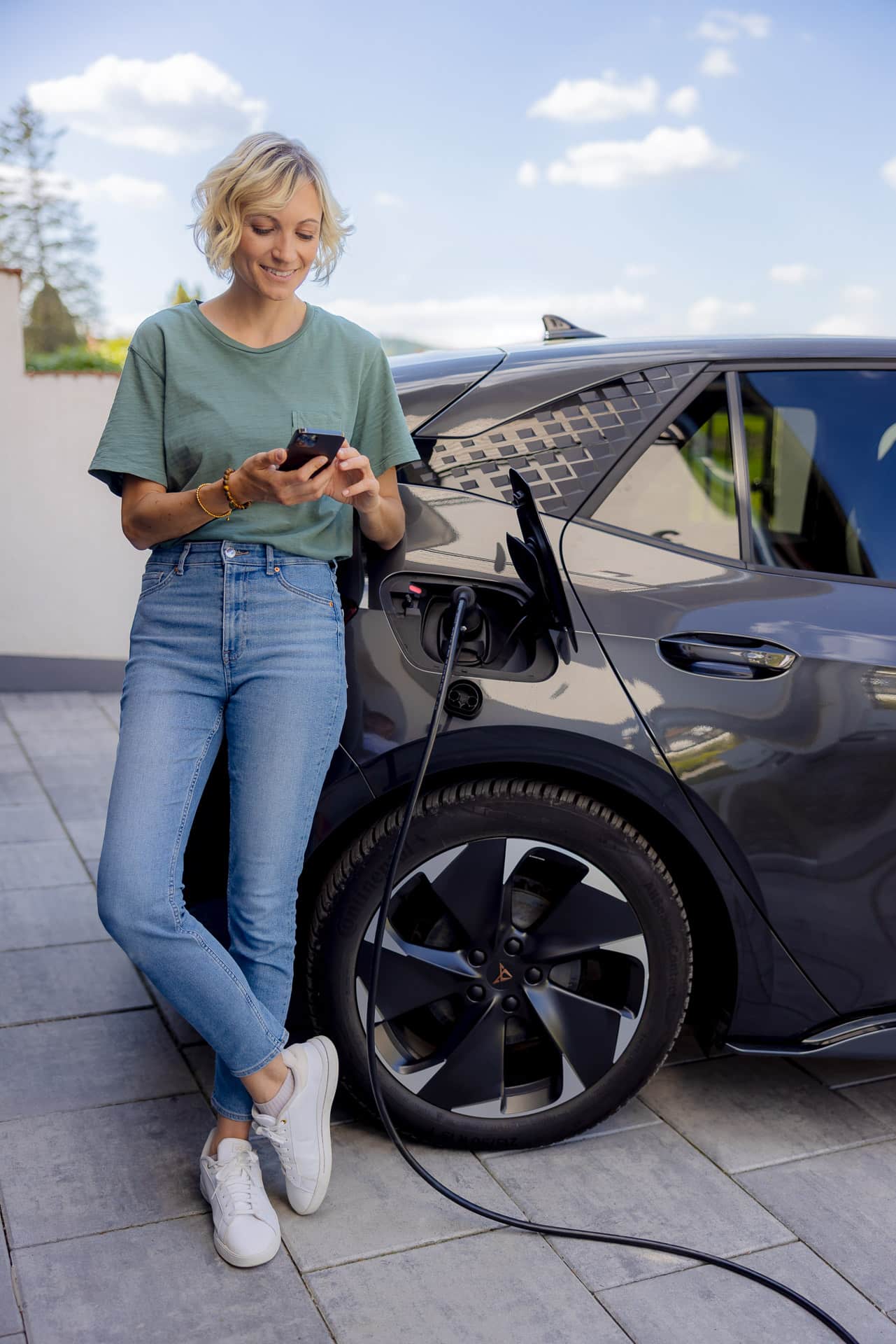 Kvinde ser på sin APP mens hun lader elbilen