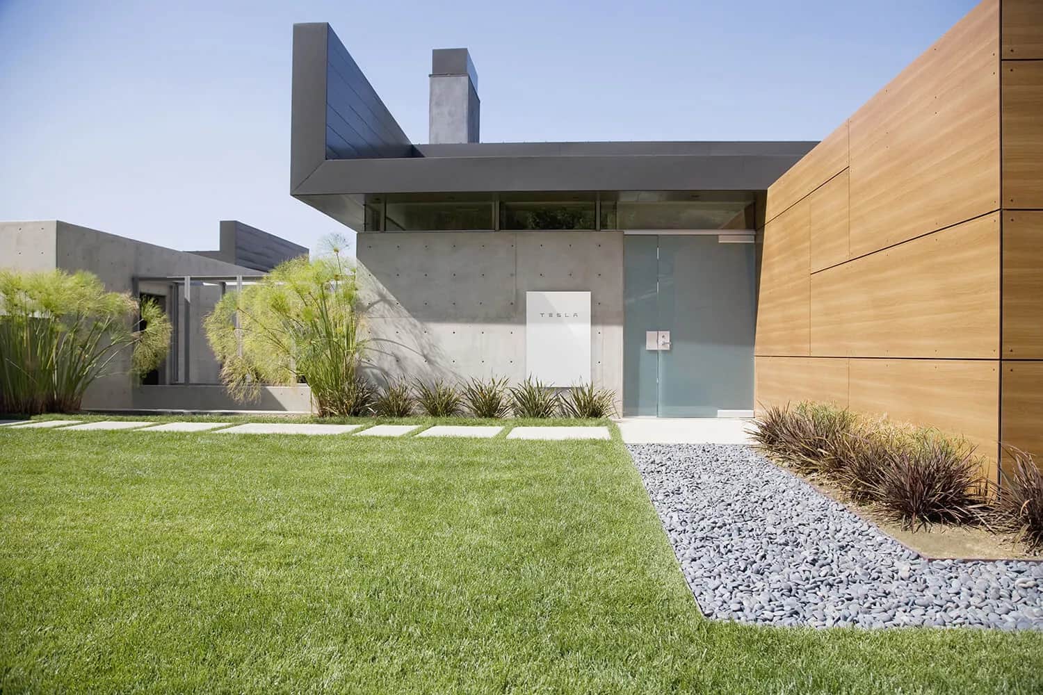 Tesla Powerwall mounted on a wall outside a modern house