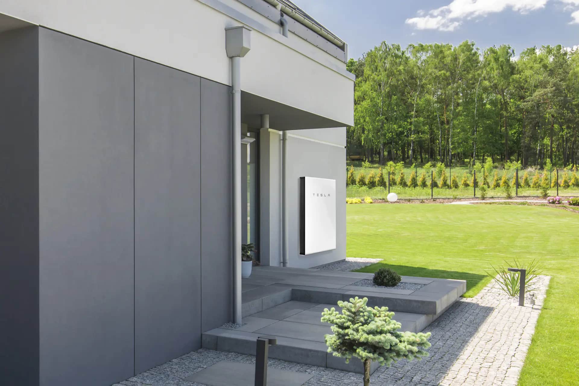 Tesla Powerwall 2 mounted on a wall outside a modern home