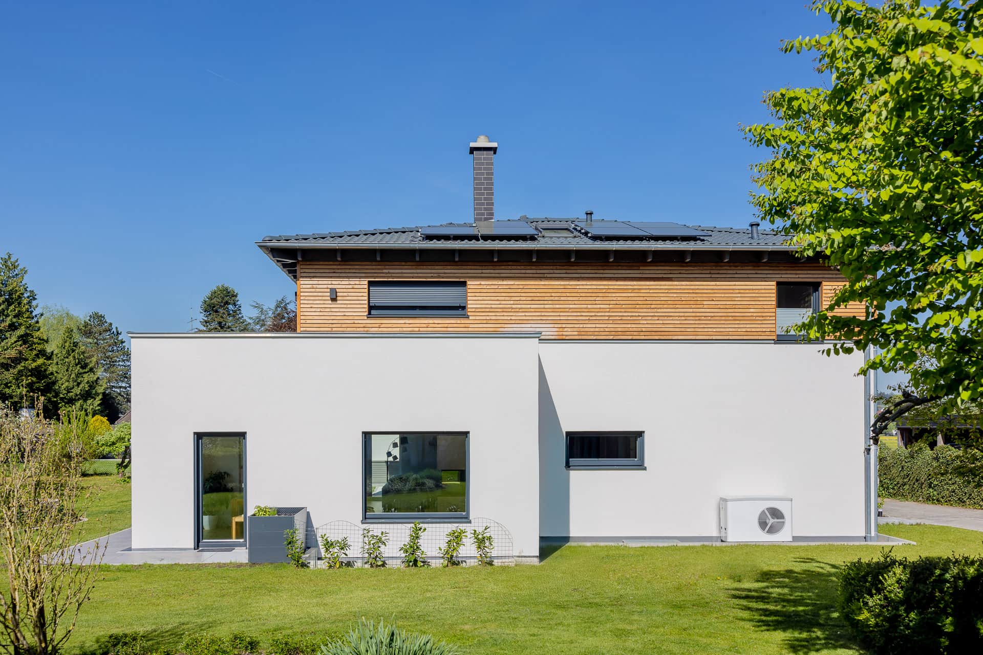 Haus mit Photovoltaikanlage und Wärmepumpe im Sommer
