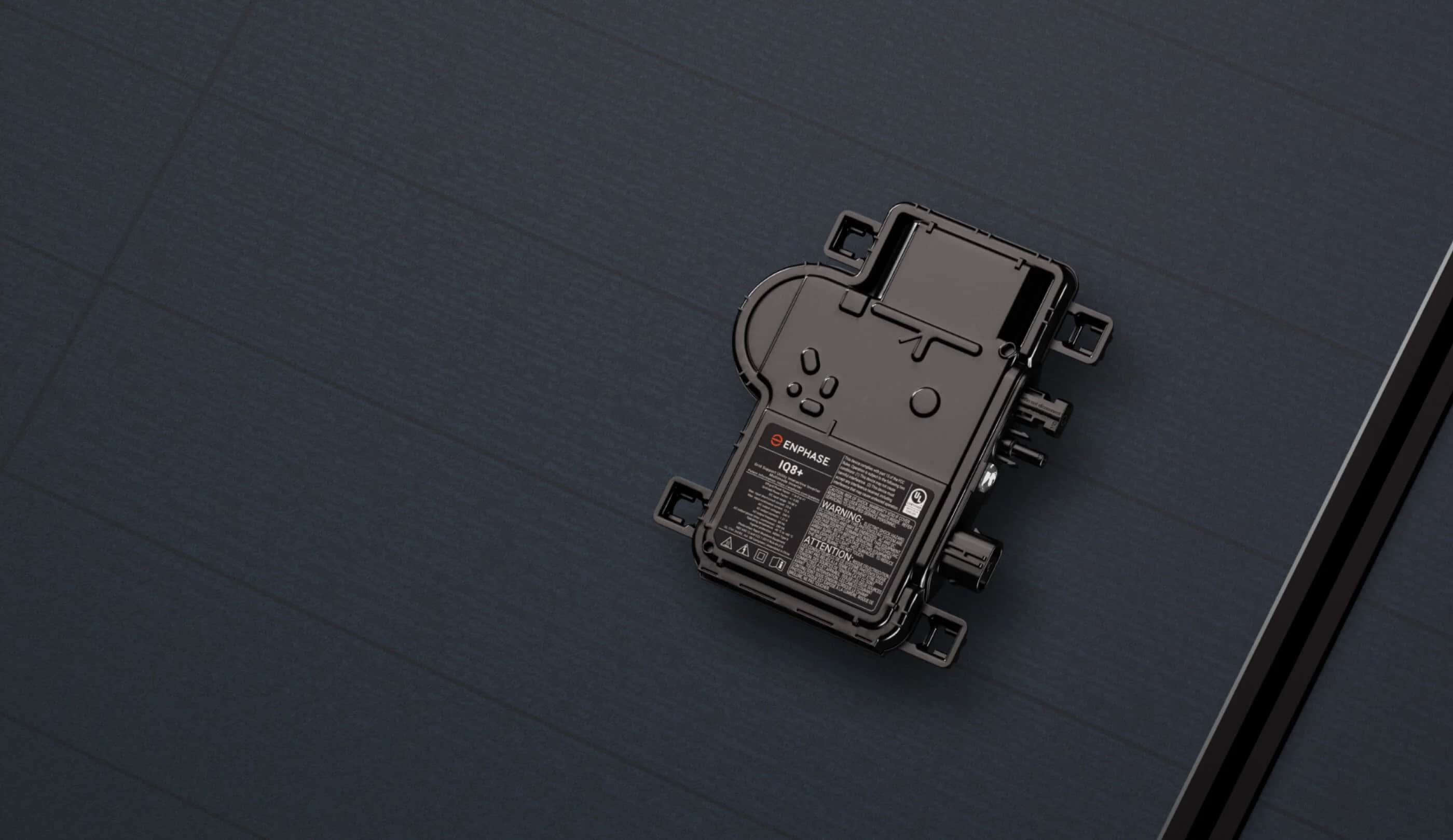 Enphase IQ8+ microinverter and mounting brackets on a dark surface