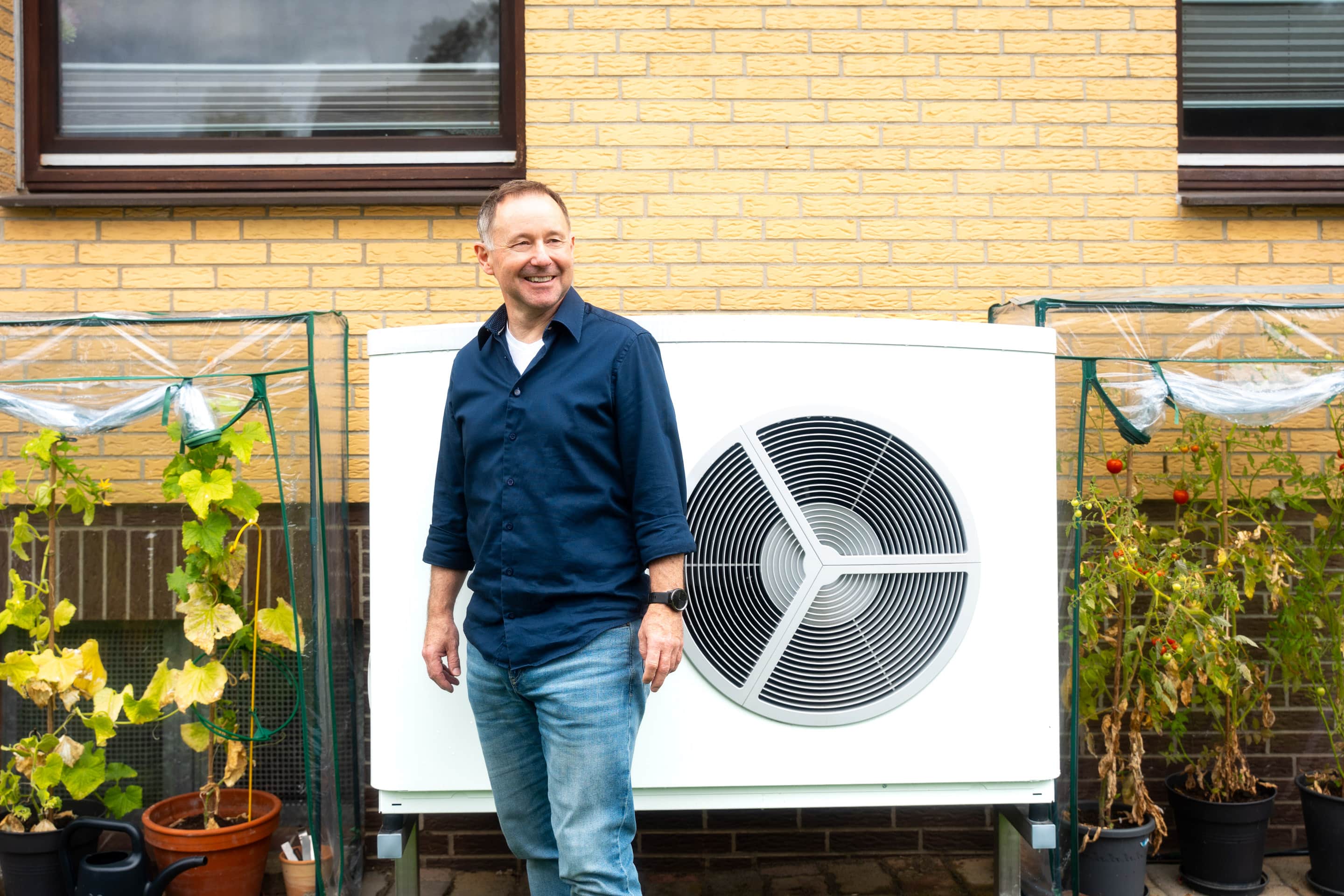 Carsten Klinge steht vor seiner Wärmepumpe im Garten