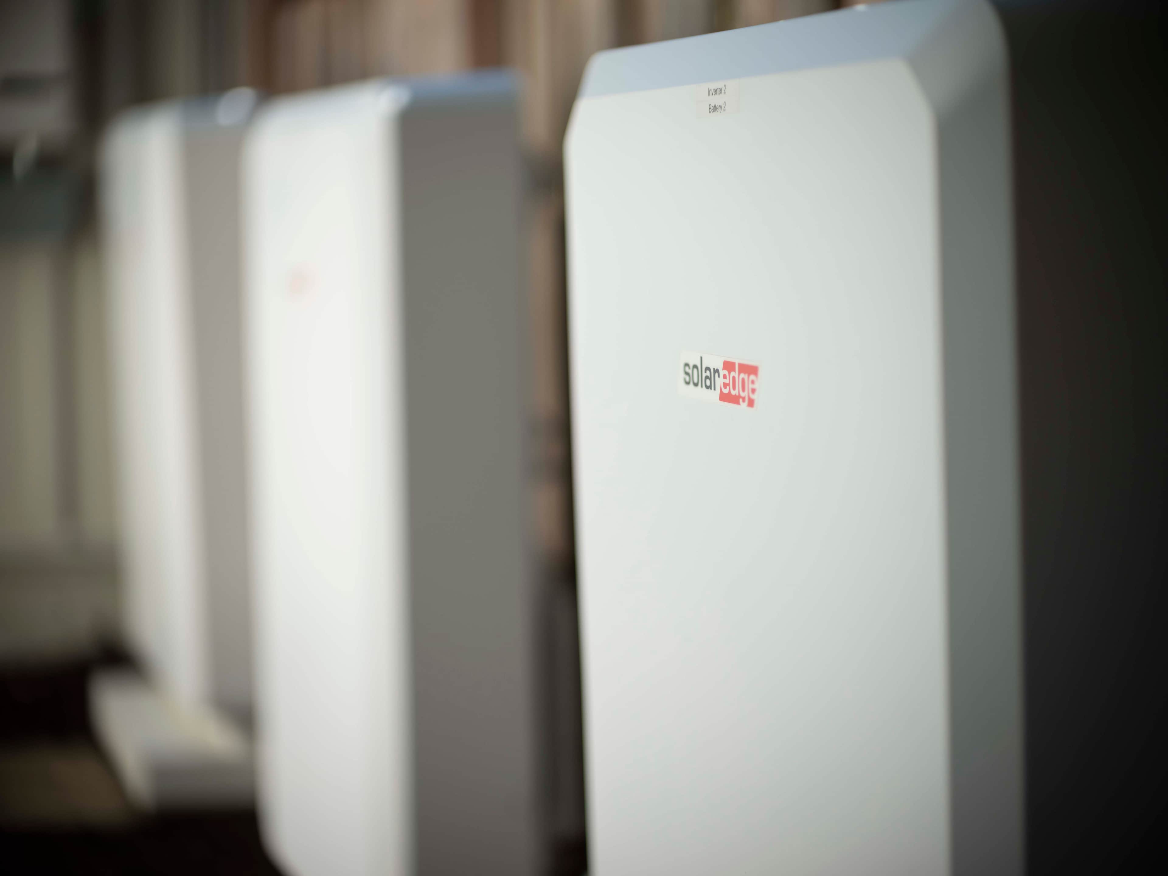  Sleek SolarEdge solar battery storage units are lined up against a blurred background