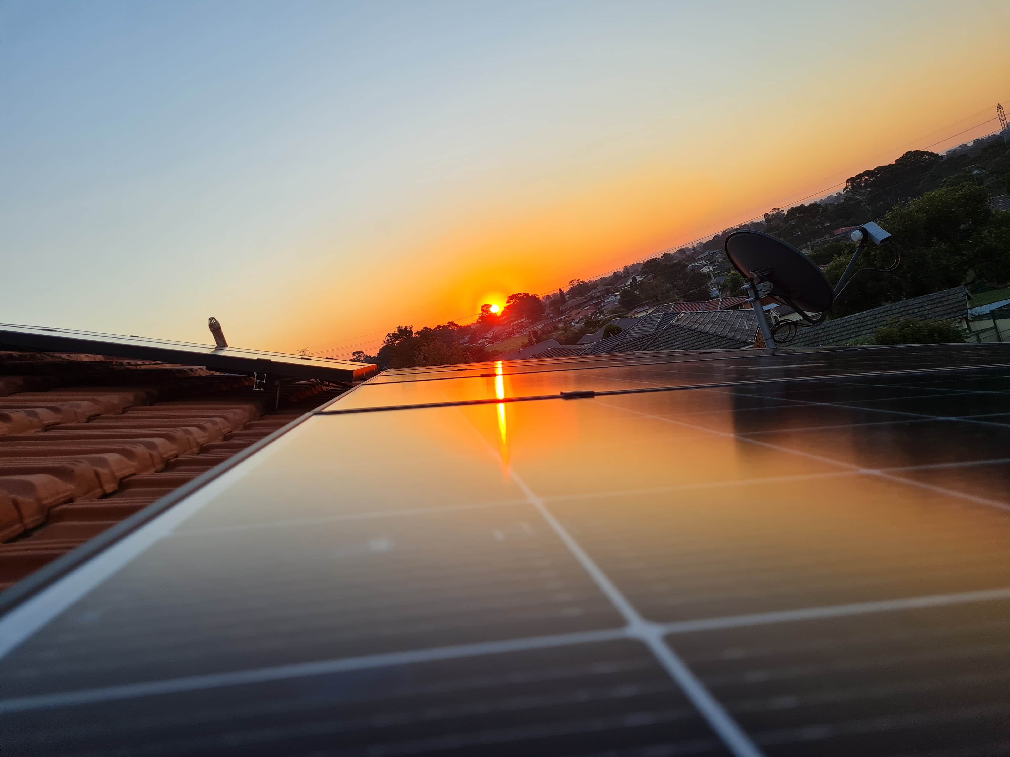sunset view over rooftops, reflecting light off solar panels