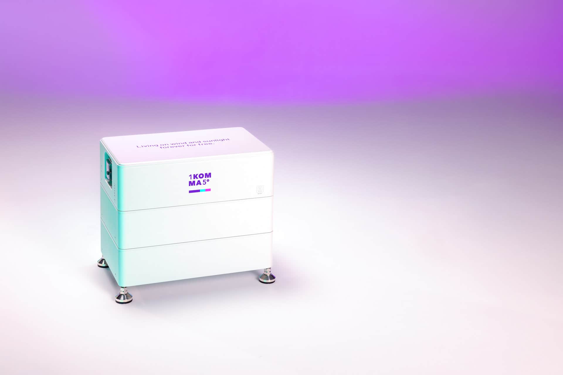 Kompakti valkoinen energian varastointiyksikkö, jossa on "1KOMMA5°"-logo, liukuvärisellä taustalla, joka siirtyy violetista valkoiseen.