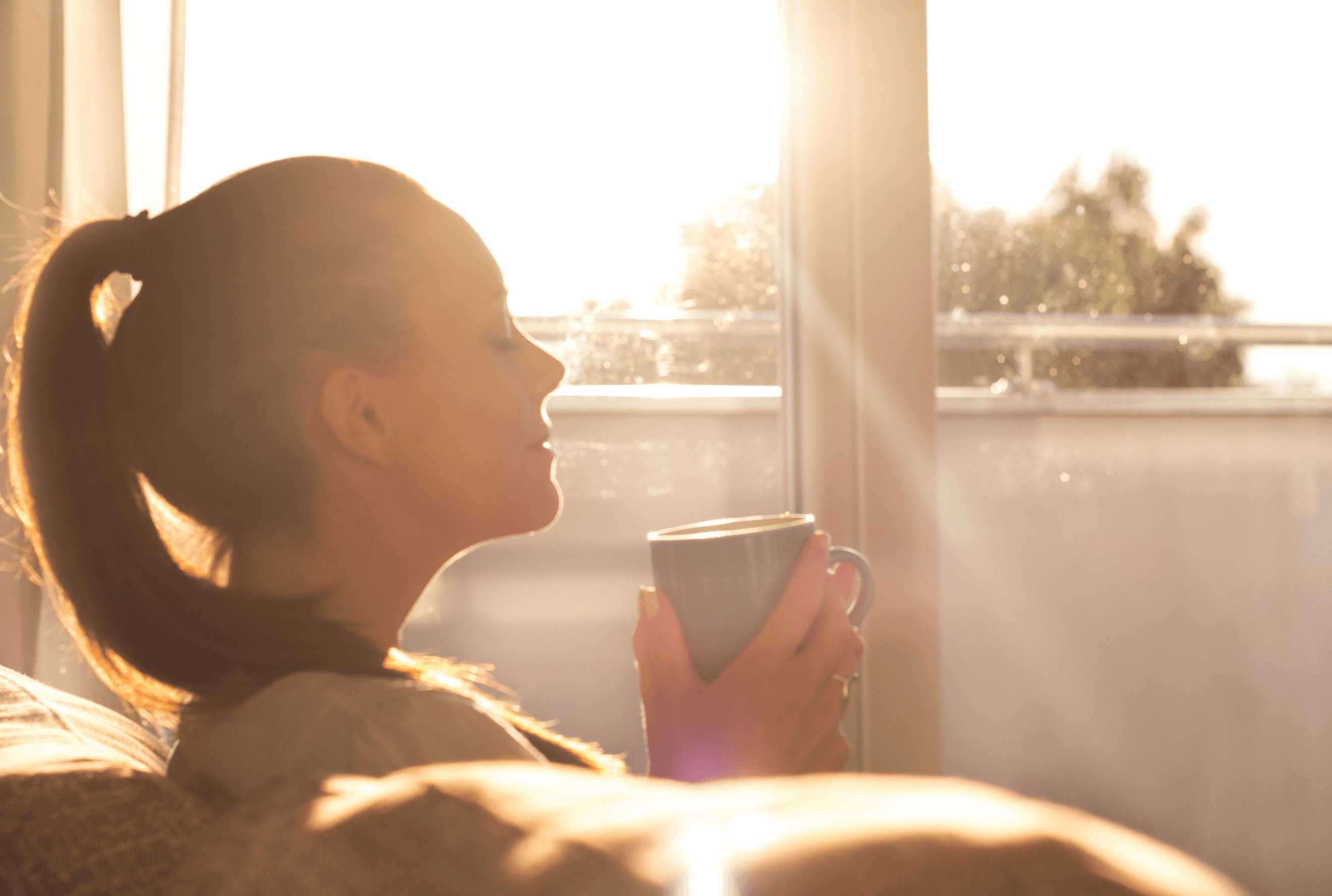 Nainen nauttii kupillisen kahvia auringonpaisteessa