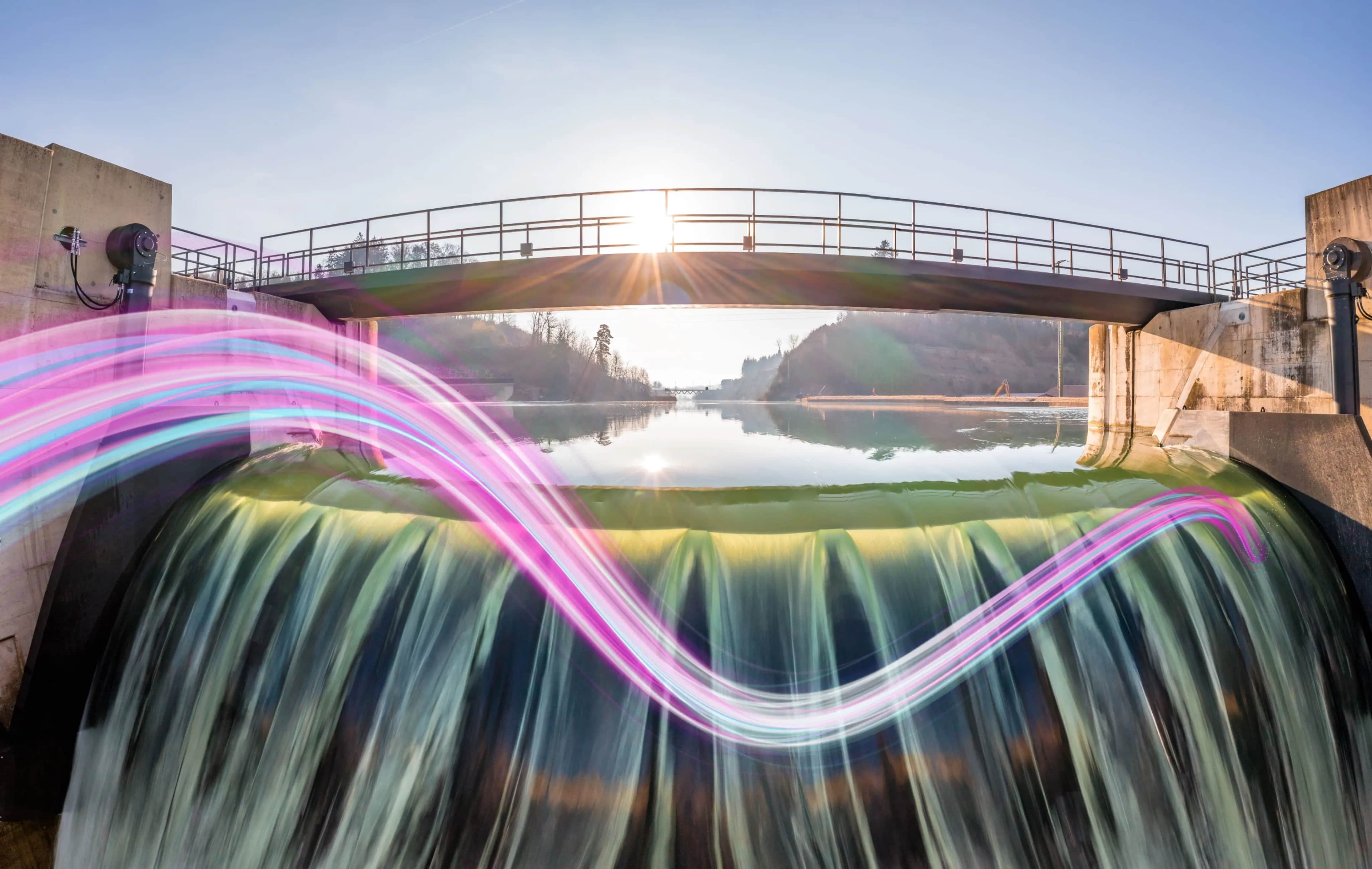 Silta padon yllä, jossa vesi virtaa alas, auringonvalo paistaa läpi ja etualalla näkyy värikäs valojuova.