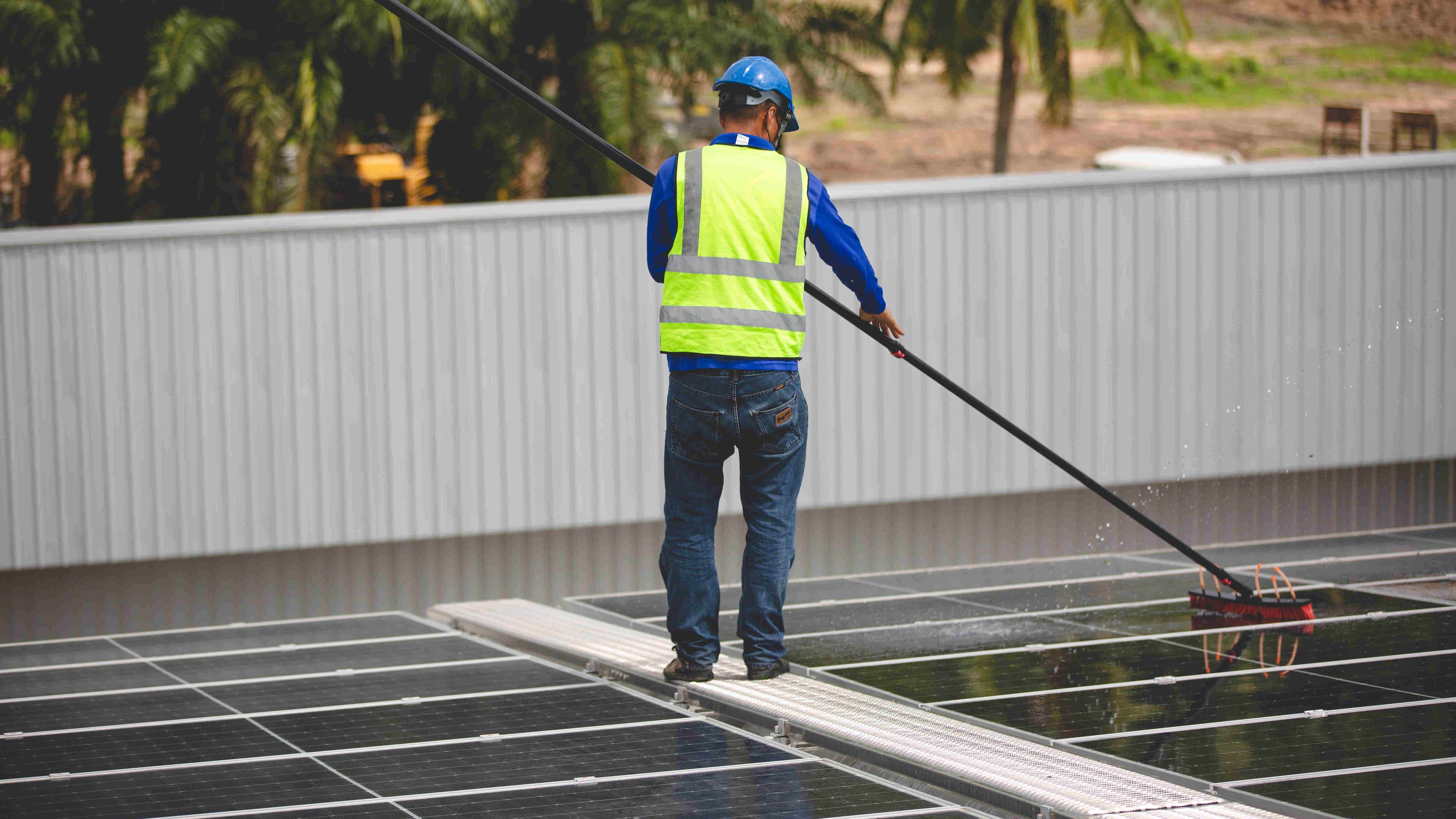 man cleaning solar panels on roof
