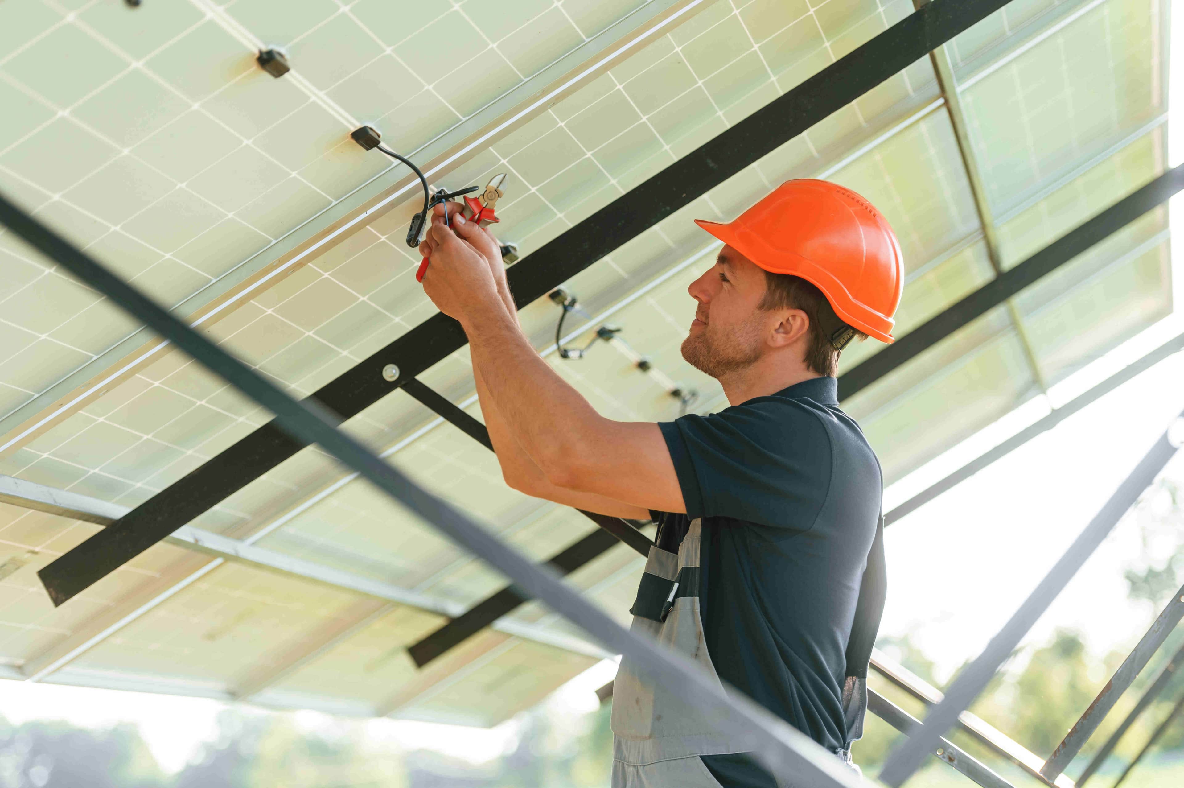 man fixing wires on solar panels