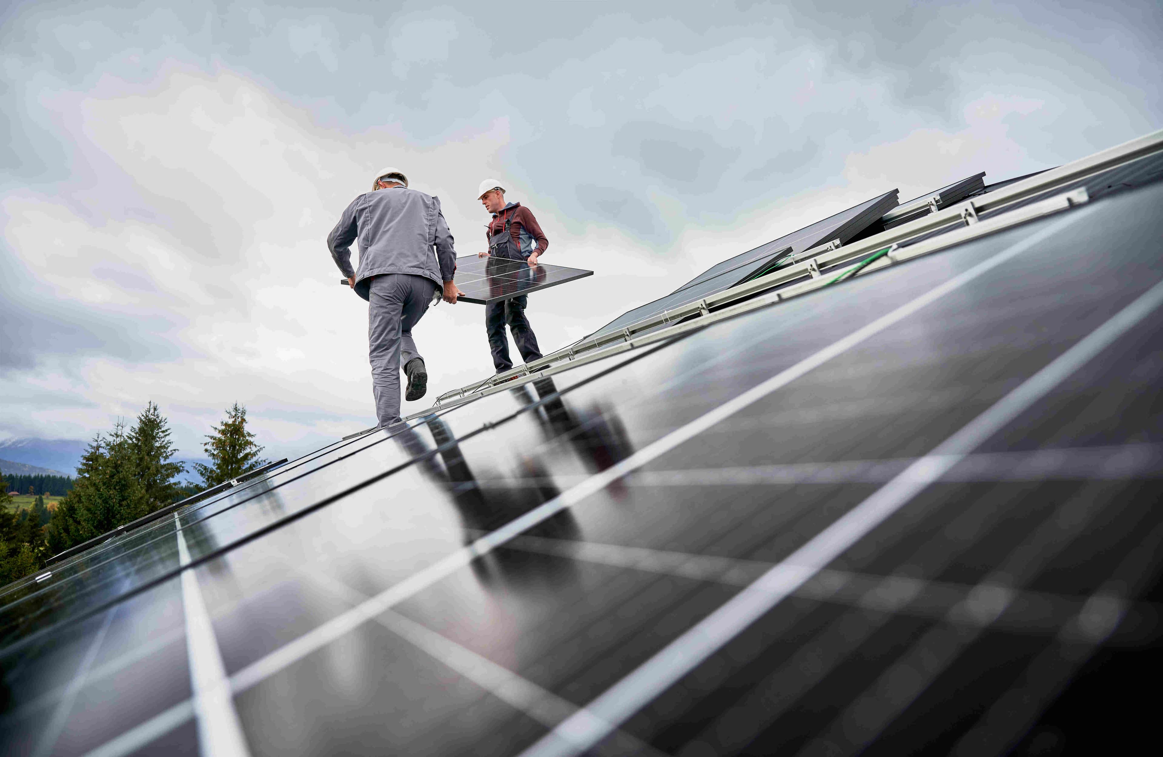 installers carrying a solar panel on a roof