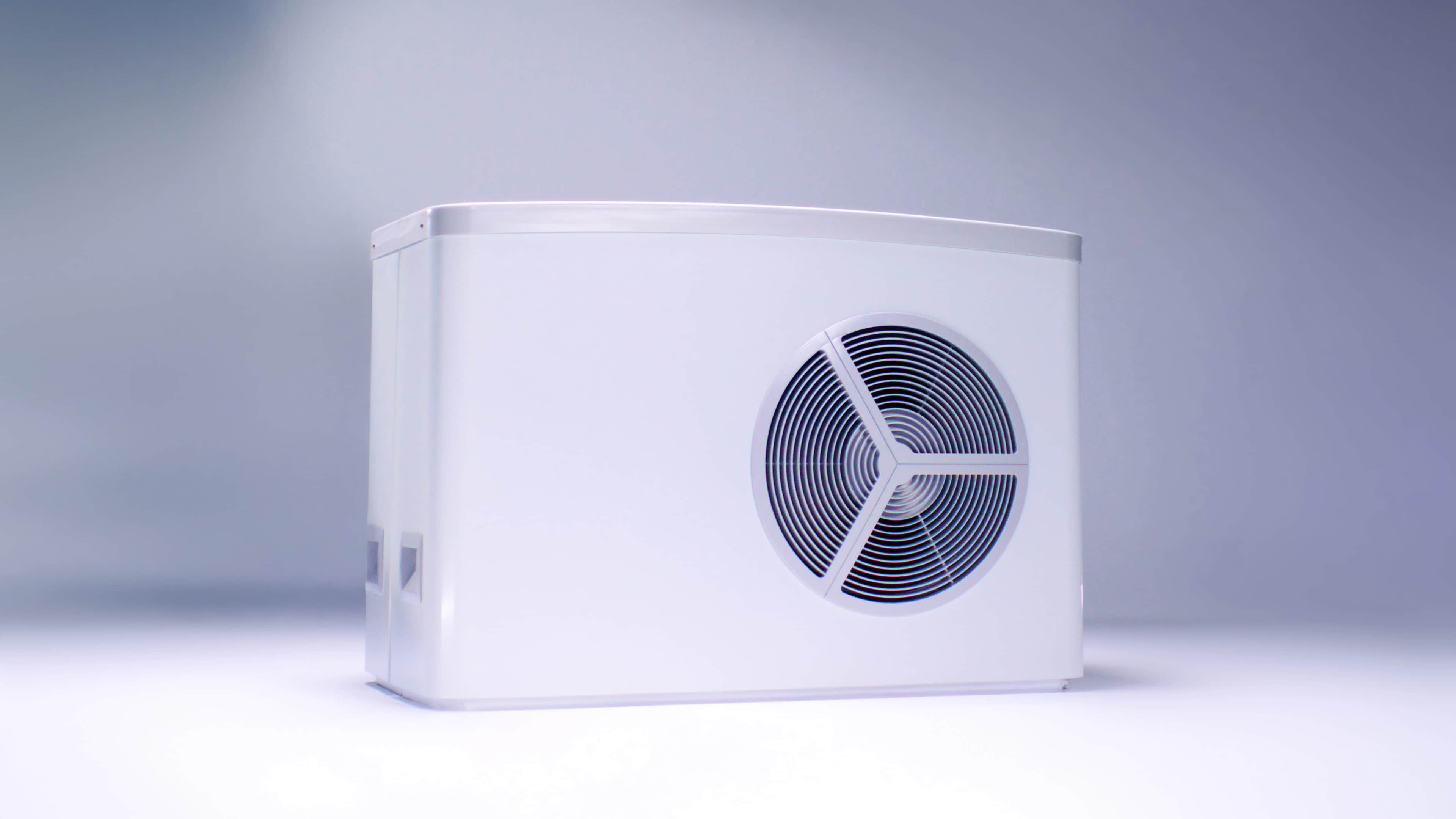 Valkoinen suorakaiteen muotoinen lämpöpumppuyksikkö, jonka sivussa on pyöreä ilmanvaihtoaukko, vaaleansinisellä taustalla.