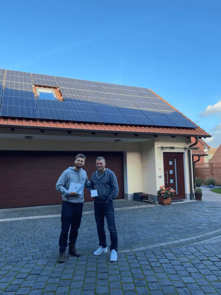 David, cliente satisfecho de 1KOMMA5° en Barcelona, sonriendo frente a su instalación de placas solares