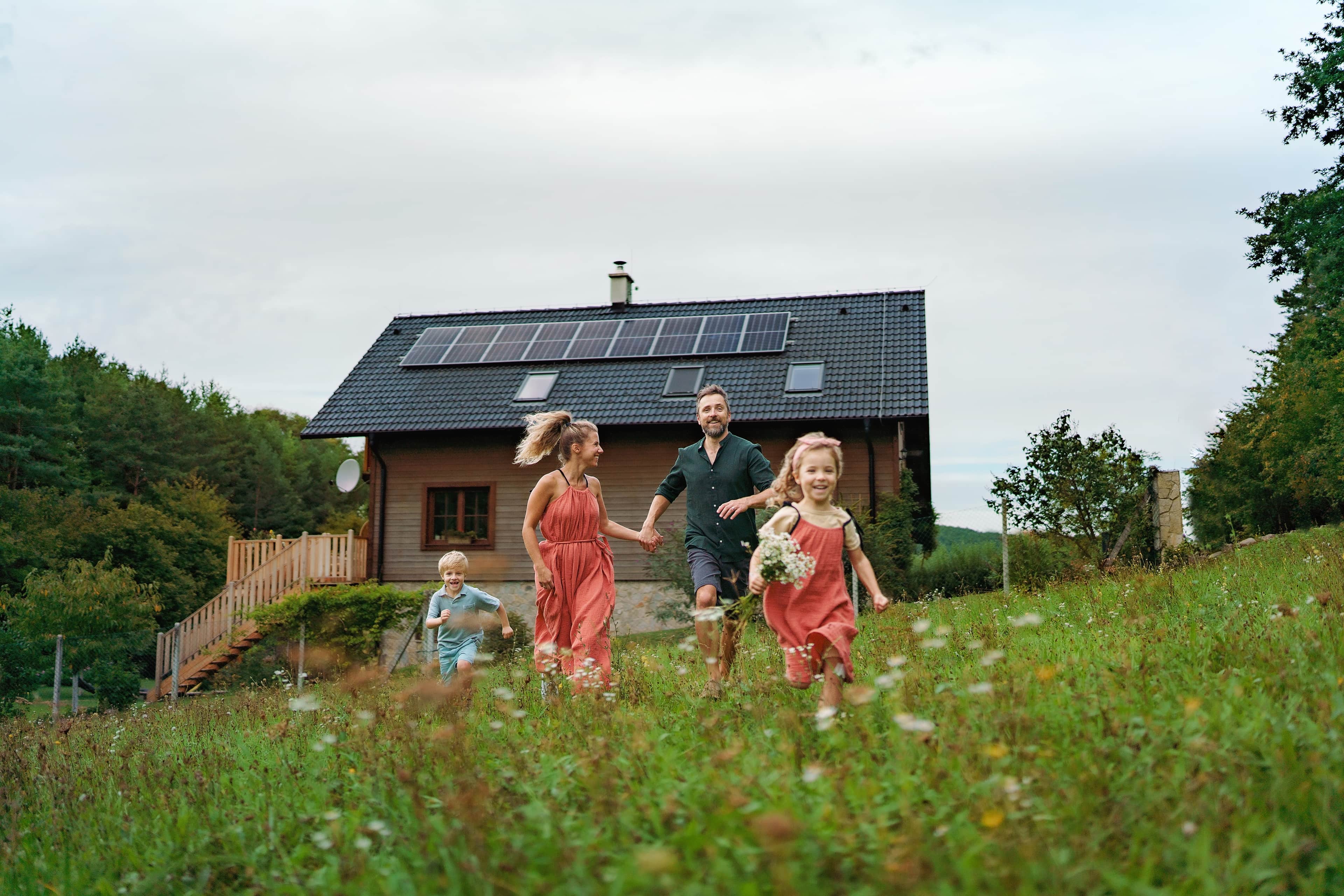 happy family running near their house with solar panels