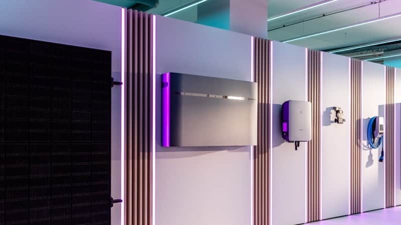 a modern display wall featuring solar panels, an inverter, and charging equipment under vibrant lighting