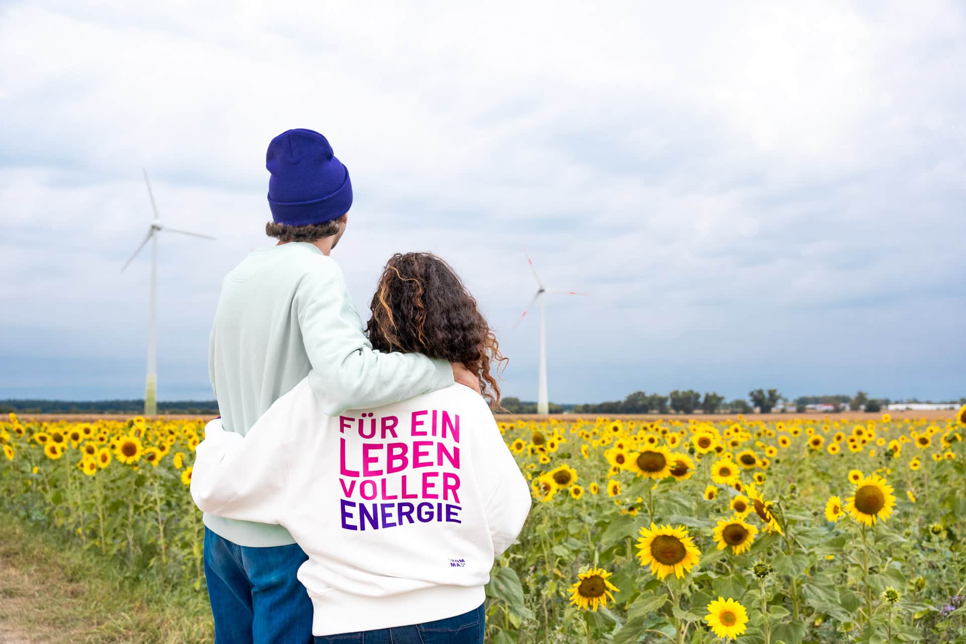 Zwei Menschen stehen vor Windrädern